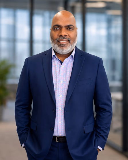 Madhu Salaksh standing in an office, wearing a navy suit